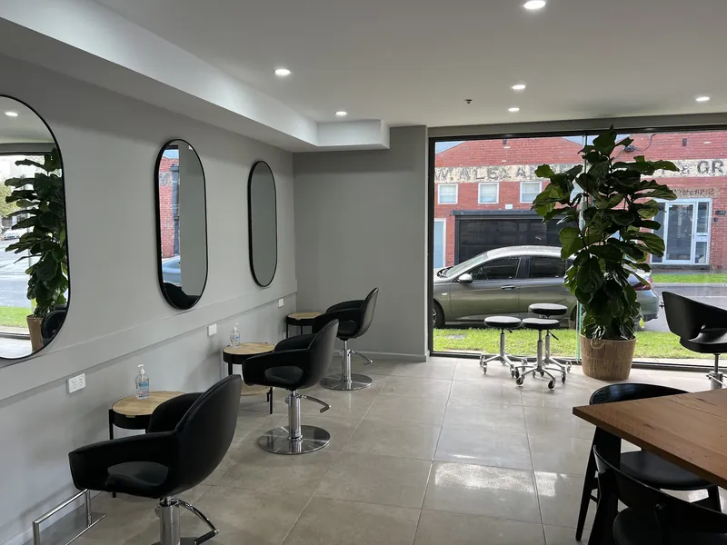 Oval mirrors and black styling chairs along the Lux Hair salon wall