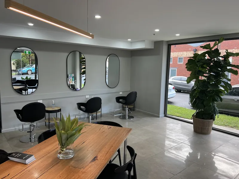 Lux Hair salon with a long timber table, tulips, oval mirrors and a fiddle-leaf fig by the window